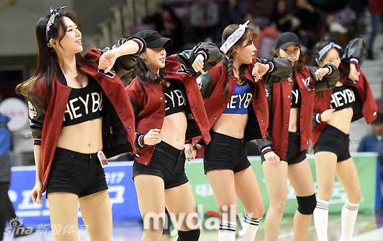 身穿亮片紧身衣的啦啦队员在聚光灯下绽放自信微笑，每一个手势都充满了感染力十足的青春气息