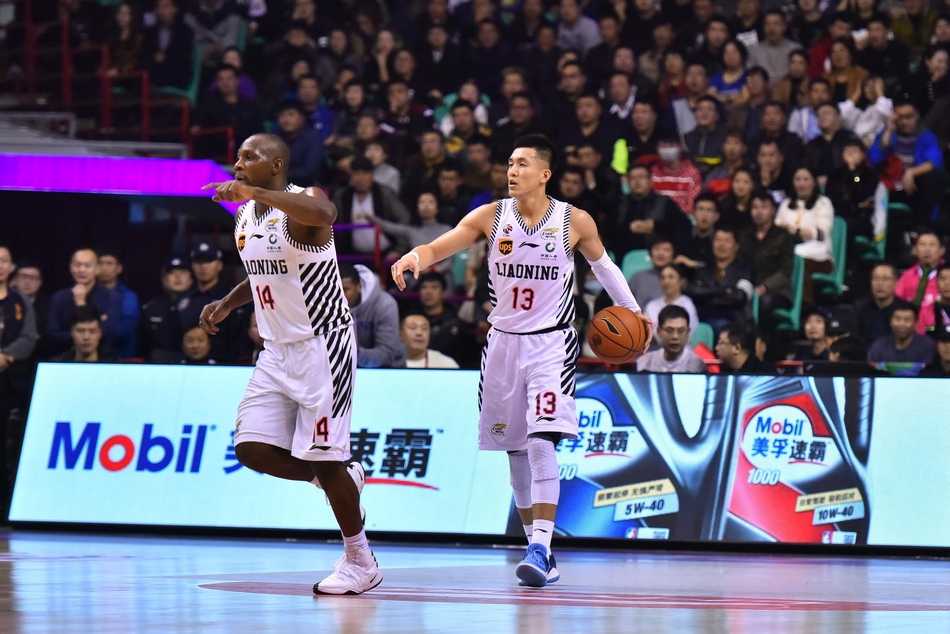 郭艾伦在两人夹击防守下高高跃起，试图完成一次难度极高的上篮，他身前的防守队员奋力起跳封盖。