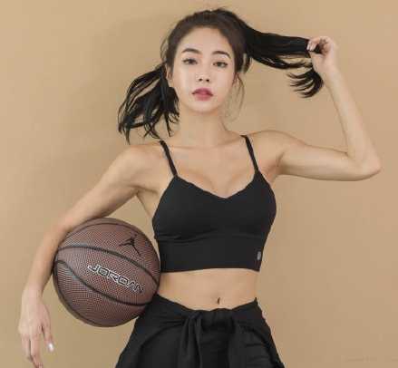 在夕阳余晖的映照下，一位身材高挑的篮球美女扎着利落的马尾，指尖轻盈地旋转着篮球，眼神中透露出专注与自信，健康的小麦色肌肤闪耀着运动后的光泽。