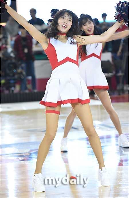首尔学生体育馆篮球盛宴,啦啦队女神舞台绽放引爆全场 比赛高潮时刻,啦啦队员面对观众席绽放灿烂笑容,双手高举指向天空,调动全场球迷的欢呼情绪。
