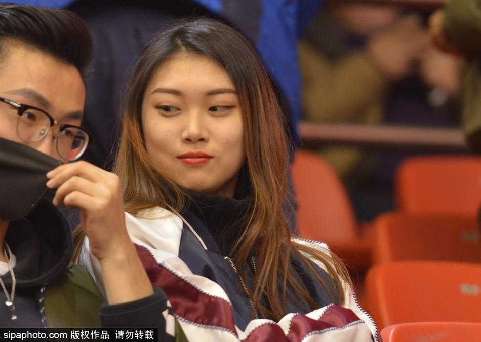 在体育馆明亮的灯光映照下，她的五官显得愈发立体。眼神透过赛场的喧嚣，温柔地投向远方，嘴角似乎带着一丝若有若无的浅笑，那种由内而外散发的娴静气质，让她即使在嘈杂的人群中也能立刻抓住人们的视线。