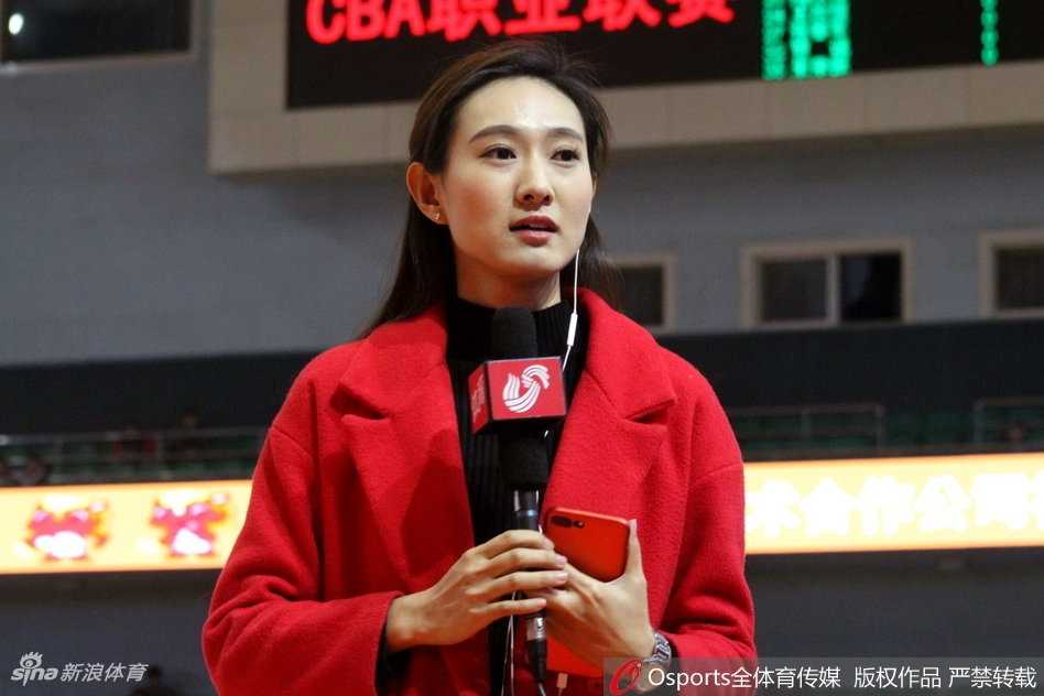 冬日的济南奥体中心外场，一位身着白色长款羽绒服的美女记者正在寒风中整理采访提纲，她回眸的瞬间，眼神中充满了对即将开始比赛的期待与专注，哈出的热气在空气中化作一团白雾。