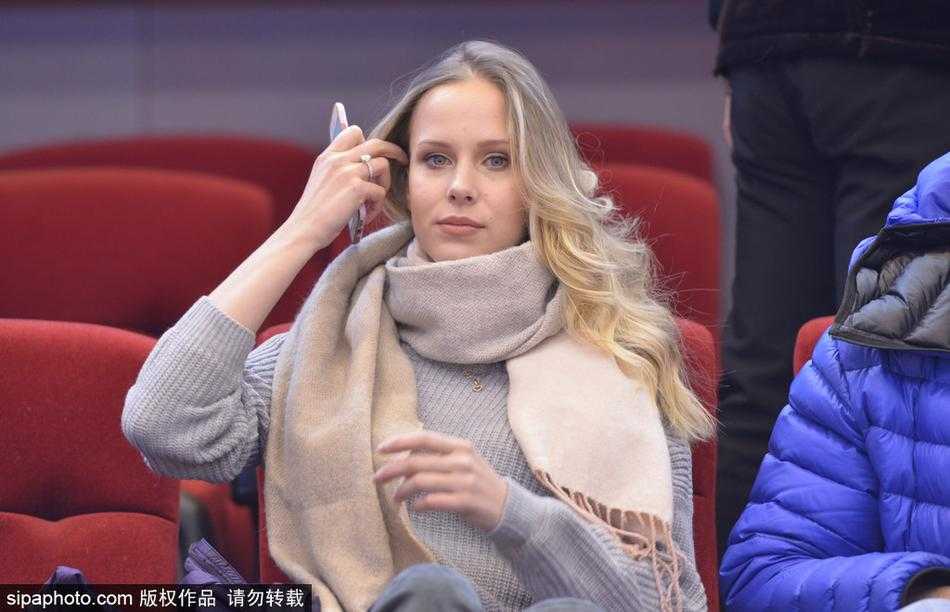 身着一袭简约时尚黑色装扮的莫泰妻子宝莲娜，在赛场看台上回眸一笑，金发如瀑，优雅气质仿佛让整个球馆的空气都凝固了。