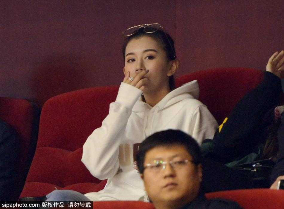 一位美女球迷在人群中回眸，自信地面对镜头，她的眼神清澈而坚定，展现出当代女性球迷的独立风采。